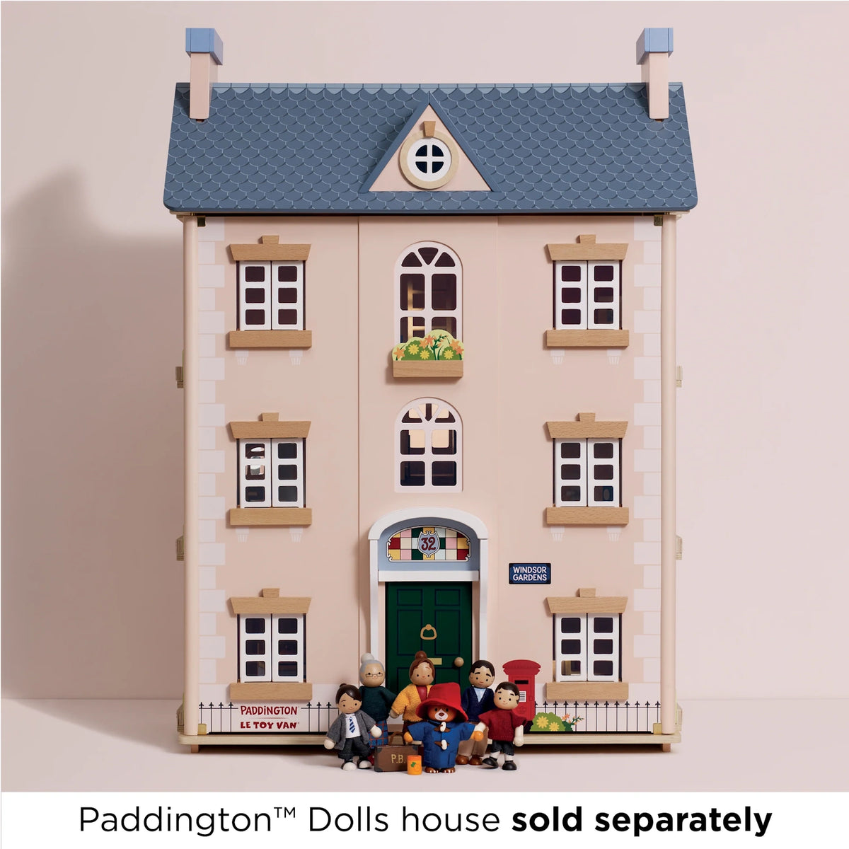 Wooden Paddington Bear and family dolls gathered outside the front door of a detailed three-story dollhouse.