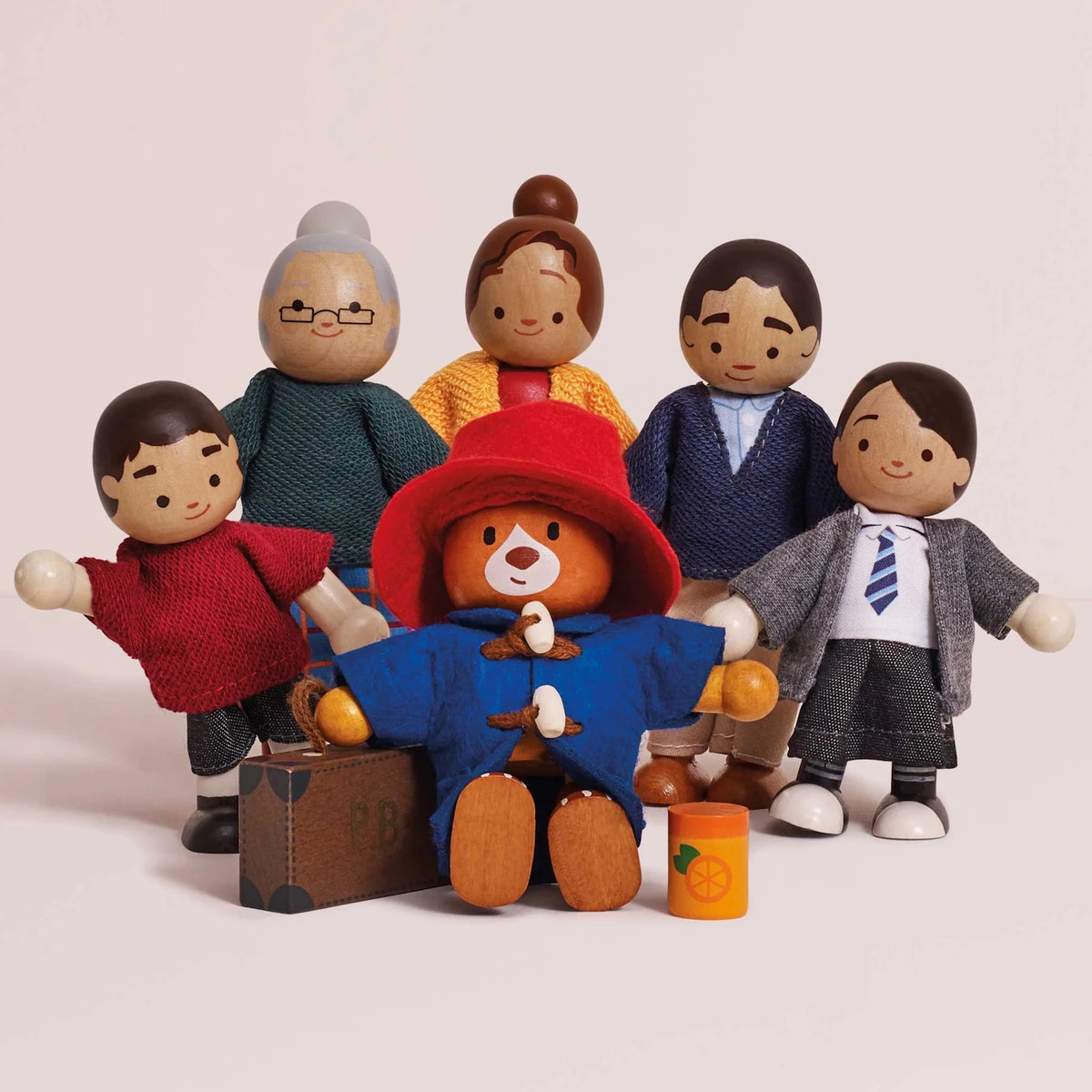 Wooden Paddington Bear toy figure sitting in front of five Brown family wooden character dolls on a white background.