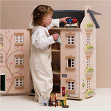 Young child playing with a wooden dollhouse and placing a Paddington Bear figure into an upper-floor bed.