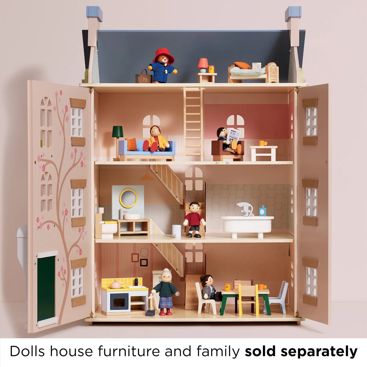 Open dollhouse with furniture and wooden figure characters on three floors, plus Paddington on the top level.