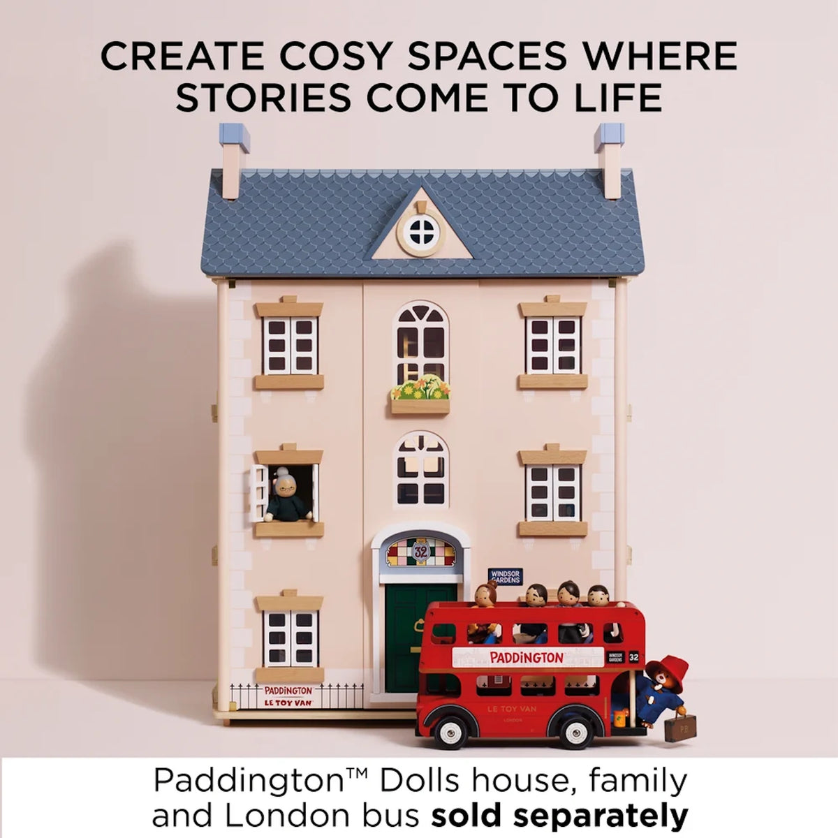 Wooden dollhouse with a London bus and Paddington figure outside.