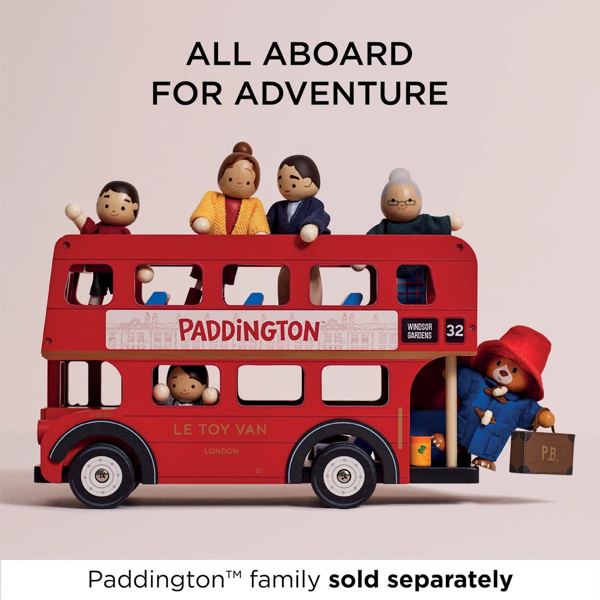 Red wooden toy London bus carrying wooden people figures, with Paddington Bear getting on at the rear.