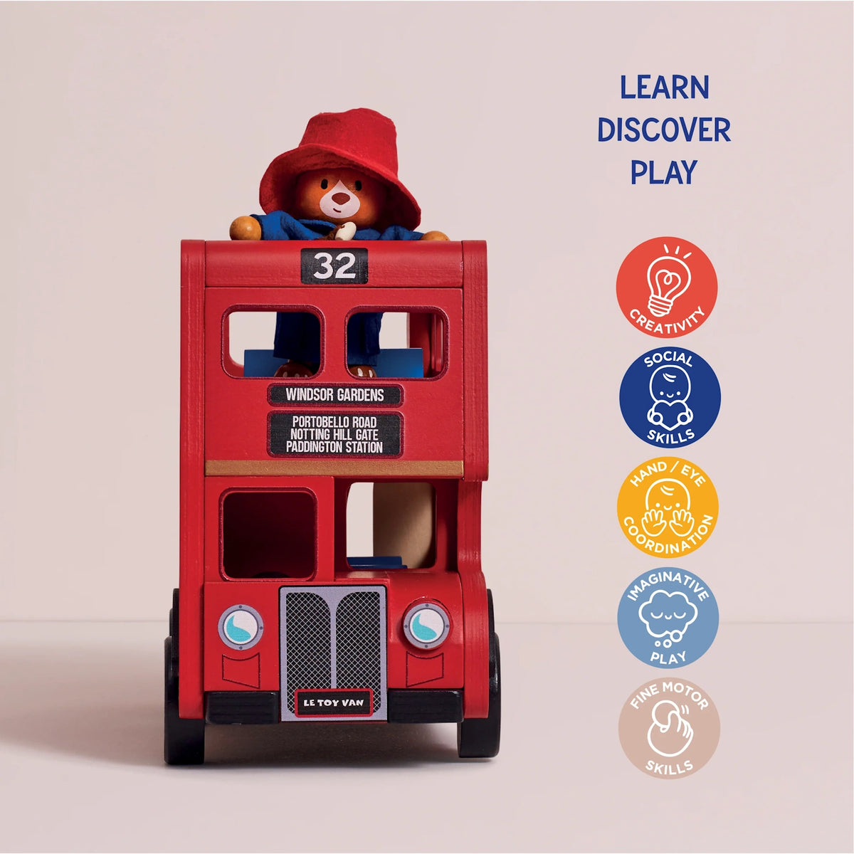 Front view of a wooden red London double-decker bus toy with a Paddington Bear figure peeking out from the top deck.