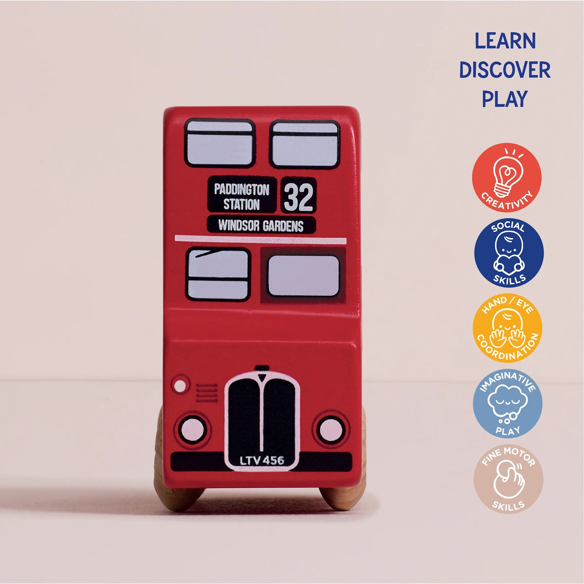 Front view of the red toy London bus with Paddington Station destination, accompanied by developmental icons.