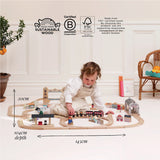 A child playing on the floor with a wooden train set, featuring overlaid dimensions and sustainability logos.