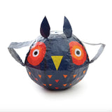 A balloon shaped like an owl with dark blue coloring, large red eyes, a yellow beak, and small triangular patterns. It has a playful and whimsical appearance.