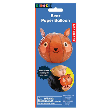 Blue packaging of a Kikkerland Bear Paper Balloon featuring an orange bear face balloon. A child blows it up. Text warns of choking hazards.