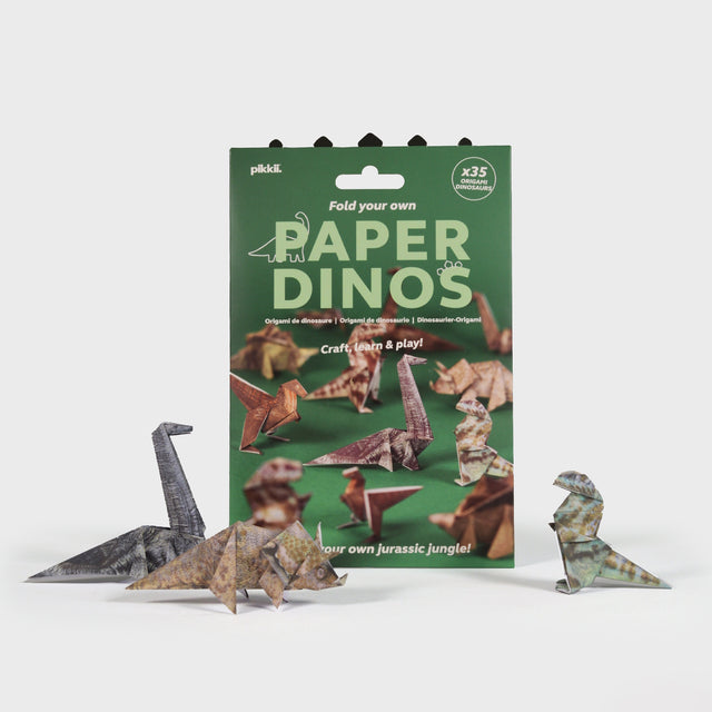 Paper Dinos origami kit packaging with folded paper dinosaurs sitting in front of it.