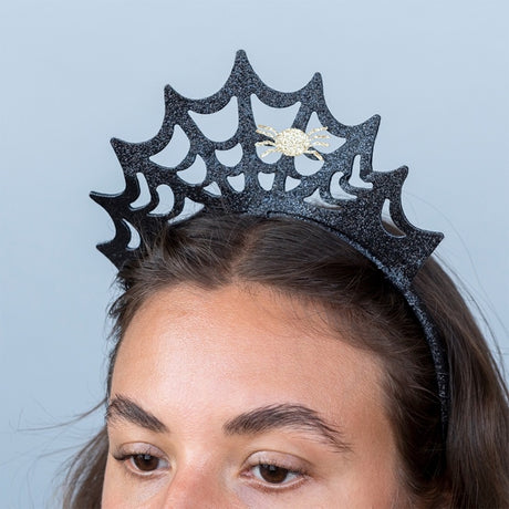 Close-up of a woman wearing a black glitter spiderweb headband with a small gold spider.