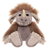 Front view of a grey plush creature with a brown mane, single horn, big feet, and a friendly, toothy grin.