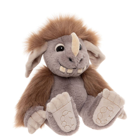 Plush monster toy with grey fur, brown mane, single horn, big floppy ears, and prominent teeth, sitting down.