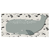 Baby cloth book spread showing a large grey whale with white spots on a cream background with ocean patterns.
