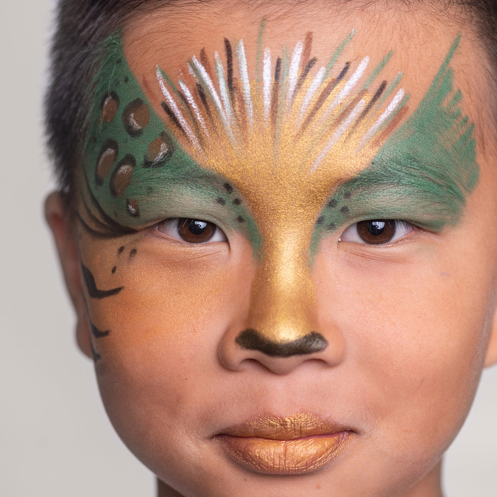 A close-up of a child with an animal-inspired face paint design in gold, green, and brown tones, resembling a jungle creature.