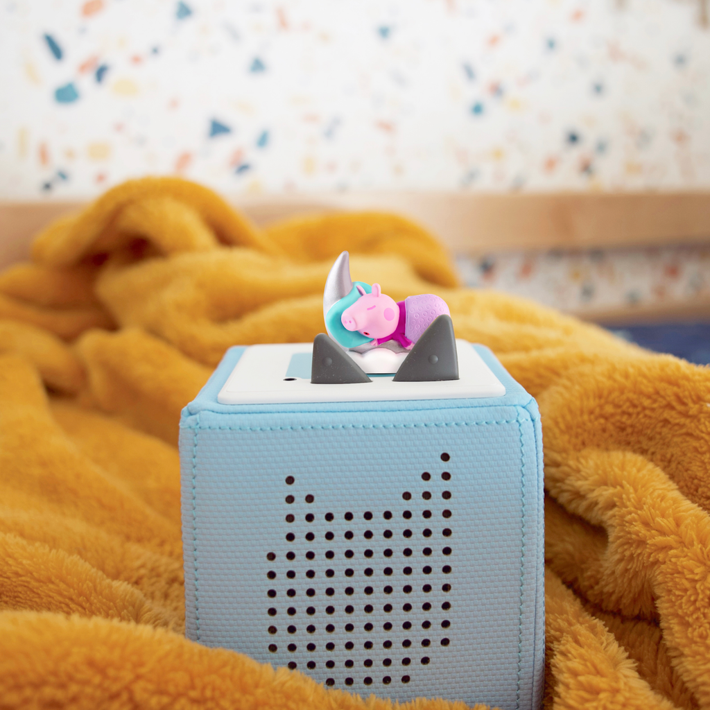 A playful Peppa Pig figurine sleeping on a silver crescent moon.