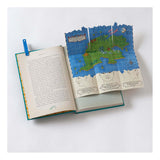 An open Peter Pan book featuring a colorful pop-up map of Neverland with blue sea and green islands.