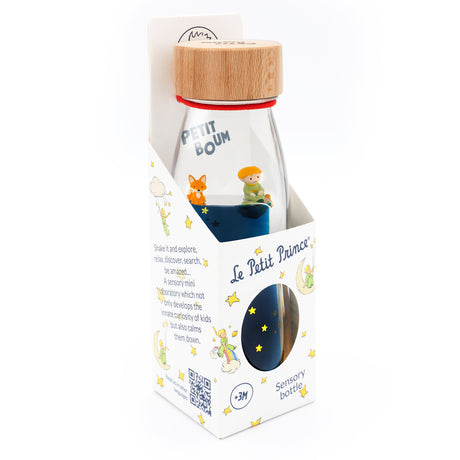 Packaging for a sensory bottle themed "Le Petit Prince." It features colorful illustrations of stars and characters, with a wooden cap and vibrant blue liquid inside. The mood is whimsical and playful.