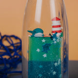 Close-up of the sensory bottle showing a miniature whale, a red-and-white lighthouse, and floating stars.