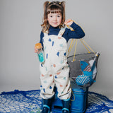 A young girl holding a sensory bottle and a net of toys.