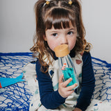 A young girl holding a sensory bottle near her face.