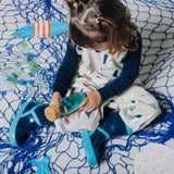 Girl sitting on a blue net and examining a sensory bottle.