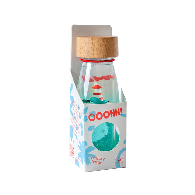 Sensory bottle in a cardboard box featuring a lighthouse, whale, and a wooden cap.