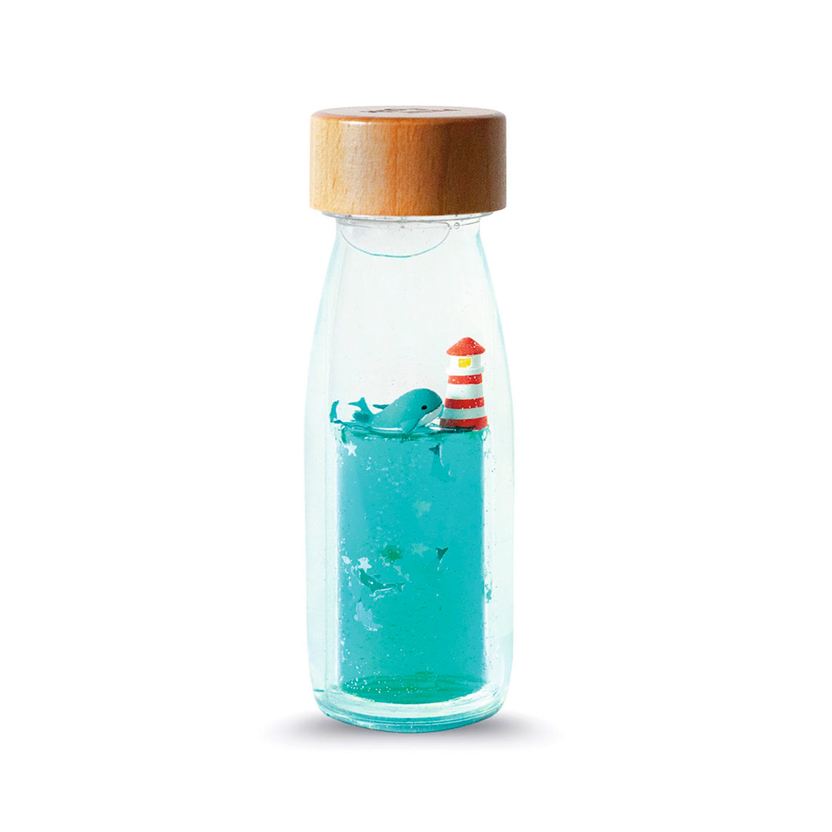 A clear sensory bottle with a wooden cap, filled with blue liquid, a miniature whale, and a lighthouse.