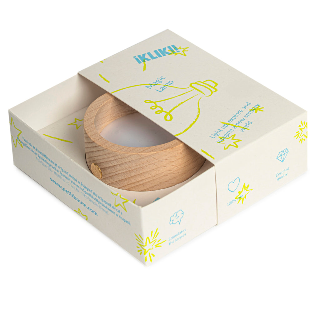 Wooden lamp in an open white box, featuring colorful doodles and text. The lamp is circular with a smooth finish, conveying a modern, playful tone.