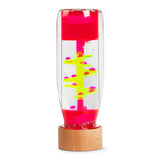 A transparent sensory liquid timer with a pink top and wooden base features neon yellow spirals and pink droplets, creating a calming effect.