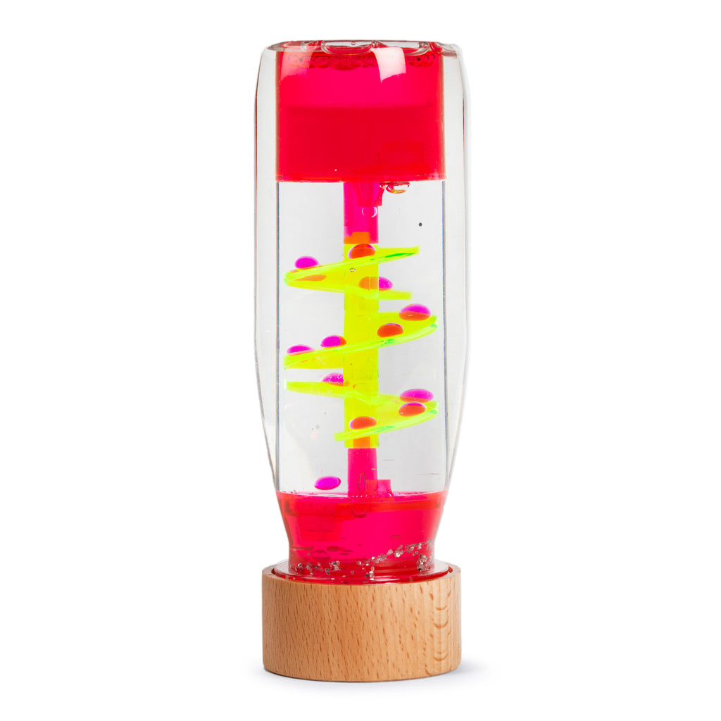 A transparent sensory liquid timer with a pink top and wooden base features neon yellow spirals and pink droplets, creating a calming effect.