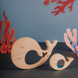 Wooden whale and baby puzzle pieces displayed against an underwater-themed backdrop.