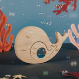 Wooden whale and baby puzzle assembled amidst floating bubbles and underwater decor.