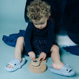 Toddler sitting on the floor and playing with the whale sensory puzzle while wearing shark slides.