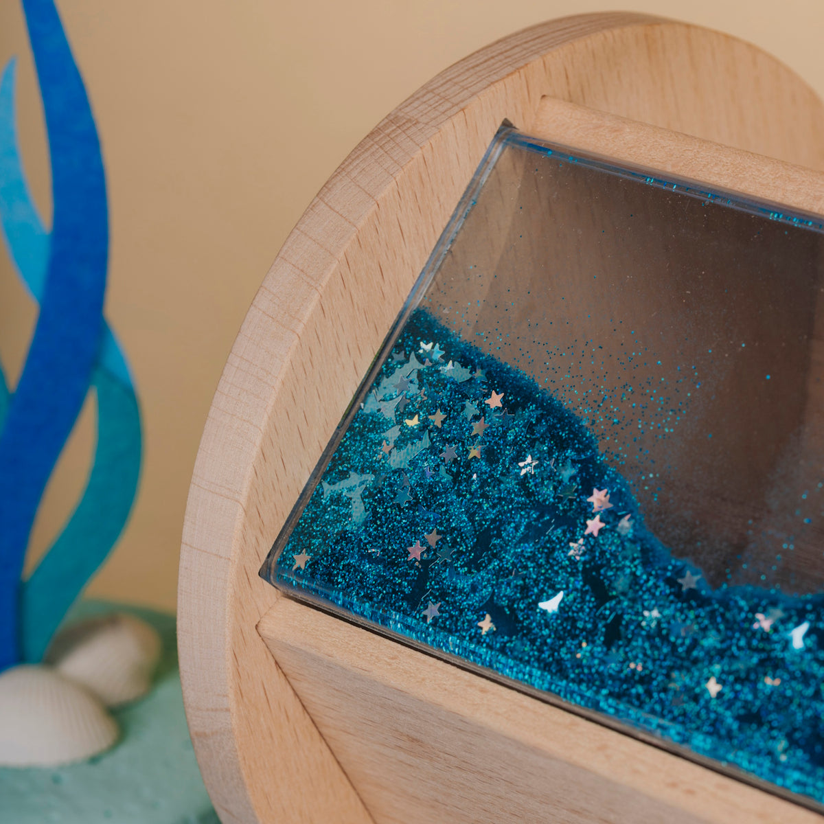 Close-up of the wooden sensory roller showing blue liquid and floating stars.