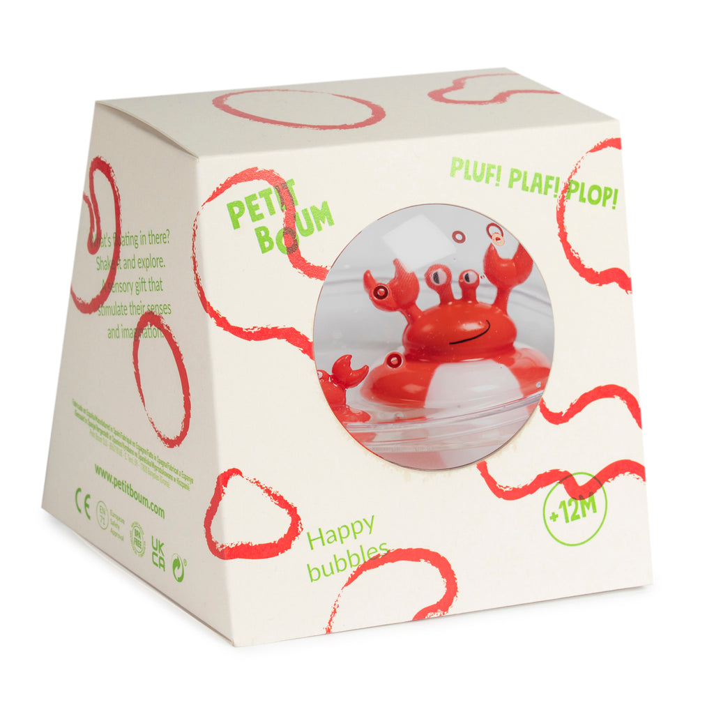 Packaging of a sensory toy featuring a red crab with expressive eyes visible through a circular window. The white box is decorated with playful red and green text and bubble designs.