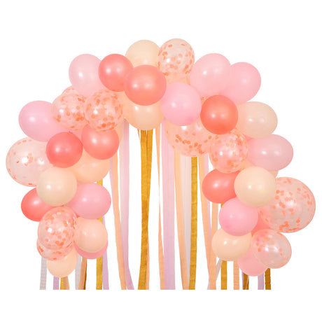 Pink balloon arch featuring blush, coral, and confetti balloons with hanging pink and gold streamer tails.