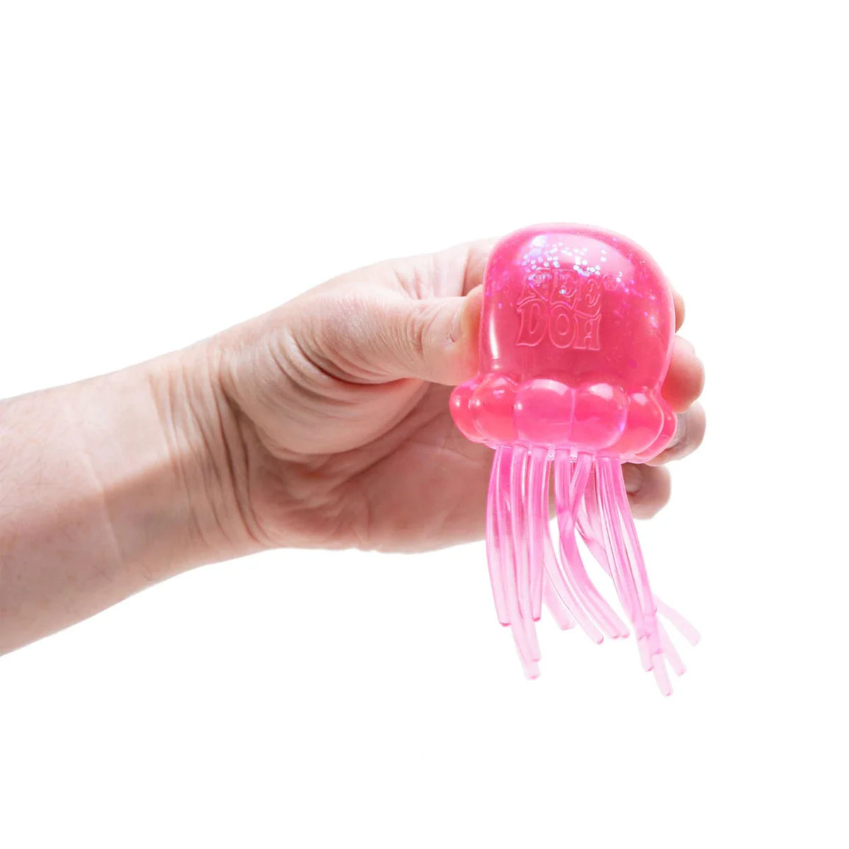 A hand holding a pink translucent jellyfish squishy toy with glitter and tentacles against a white background.