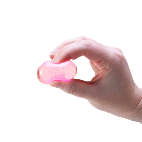 A hand squeezing a small, translucent pink oval-shaped stress toy against a white background.
