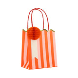 Meri Meri striped party bag with orange and pink stripes, red handles, and an orange honeycomb paper pom-pom.
