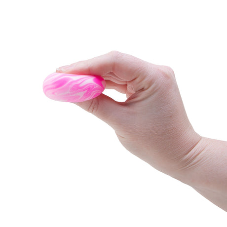 A hand squeezing a pink and white marbled Swirl Teenie NeeDoh fidget toy to demonstrate its squishy texture.