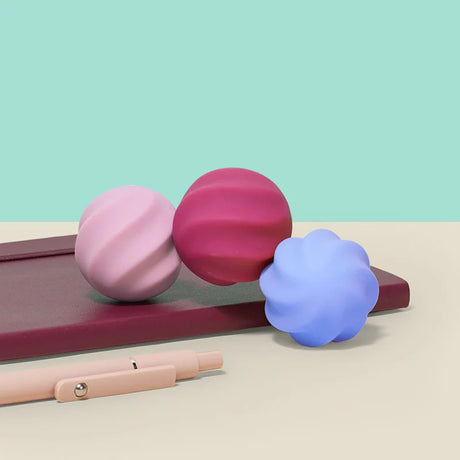 Three colorful swirled Speks Odds fidget magnets on a desk next to a pen and notebook.