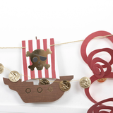 Close-up of a pirate garland showing a paper pirate ship cutout, gold coin garland, and red octopus tentacles.