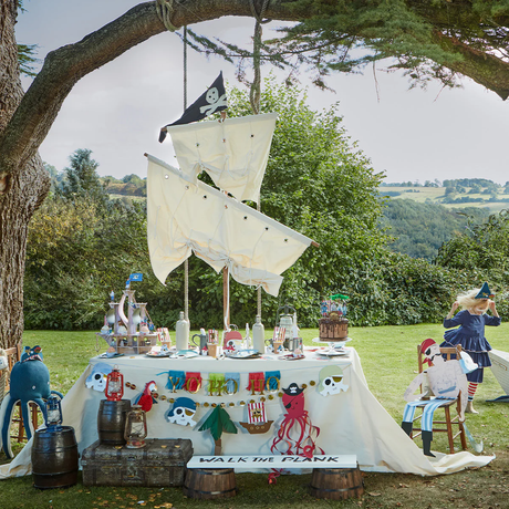 Outdoor pirate party display featuring a themed table decorated with pirate garlands and festive props.