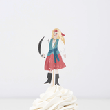 Female pirate cupcake topper holding a cutlass on a wooden pick, placed in swirled white frosting.