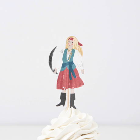 Female pirate cupcake topper holding a cutlass on a wooden pick, placed in swirled white frosting.