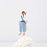 Pirate crew member topper in a red headscarf and striped pants on a wooden pick in swirled white frosting.