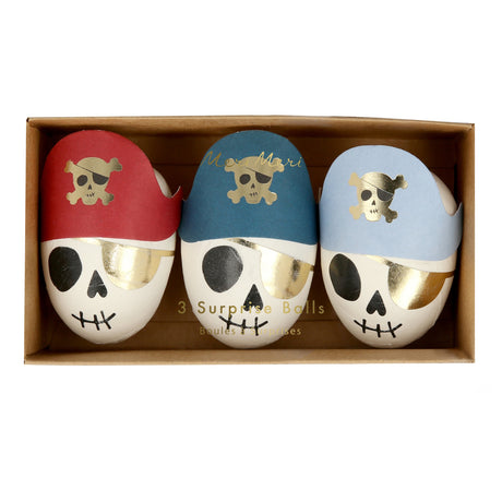 Three pirate skull surprise balls with colorful bandanas and gold eye patches in a cardboard box.