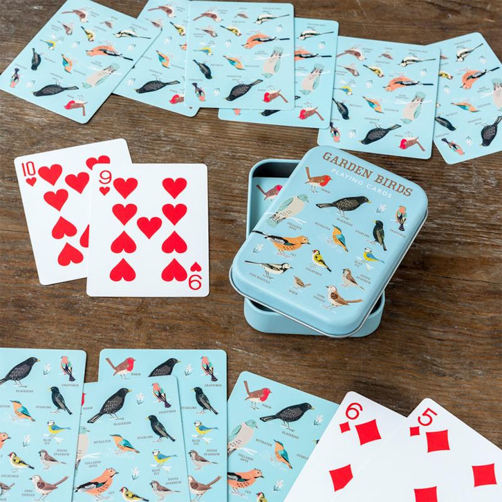 A tin of garden bird playing cards alongside a hand of playing cards showing Ace, King, Queen, and Jack in a white background.