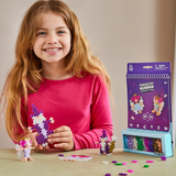 Girl playing with Plus-Plus Puzzle by Number Enchanted Forest activity set, building 2D and 3D colorful fantasy figures.