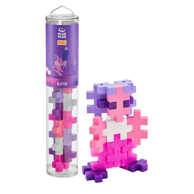 Transparent cylindrical container with colorful interlocking pieces in pink, purple, and white. Assembled figure of a pink and purple creature beside it. Fun, playful vibe.