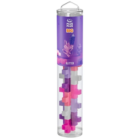 Clear cylindrical tube with colorful interlocking puzzle pieces in pink, purple, and glitter. The label reads "Plus-Plus BIG Glitter" on a purple band.